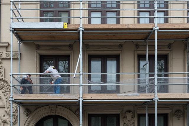 Historisches Gebäude, das renoviert wird, mit Gerüsten und Bauarbeitern im Vordergrund.